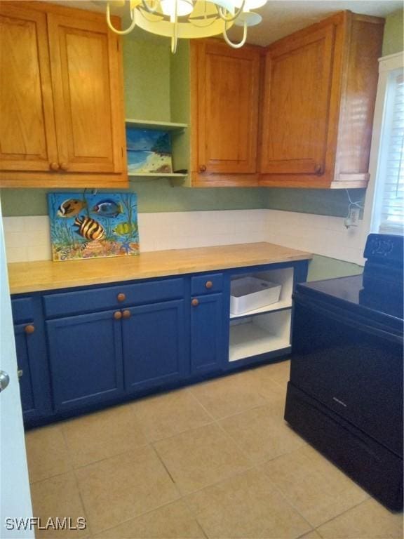 kitchen with blue cabinets, a notable chandelier, electric range, light countertops, and open shelves