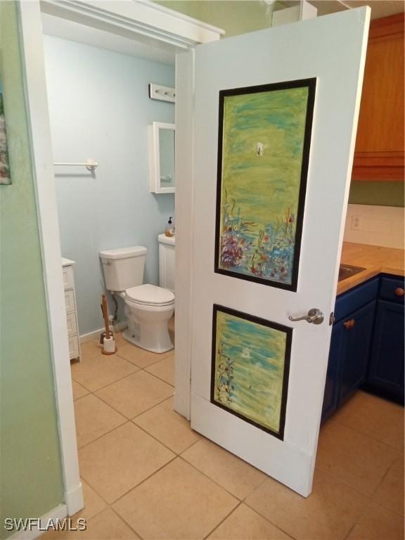 bathroom with toilet, tile patterned flooring, baseboards, and vanity