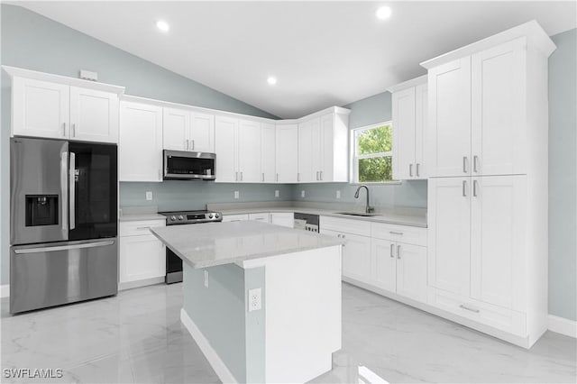 kitchen with a kitchen island, a sink, appliances with stainless steel finishes, white cabinetry, and marble finish floor