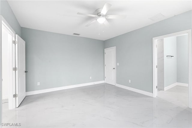 unfurnished bedroom featuring visible vents, marble finish floor, baseboards, ceiling fan, and a spacious closet