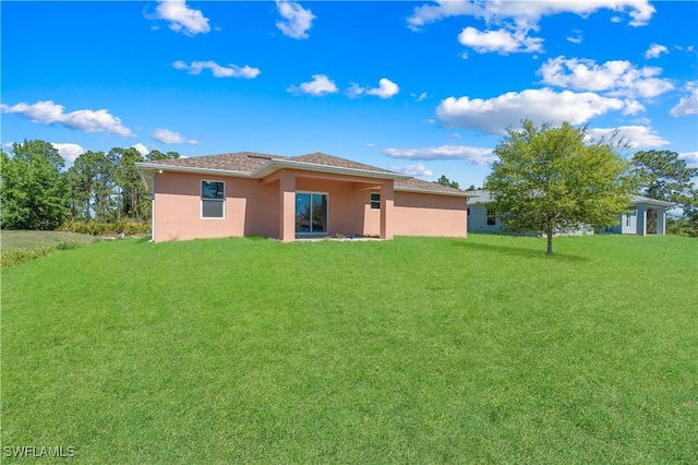 back of property with a yard and stucco siding