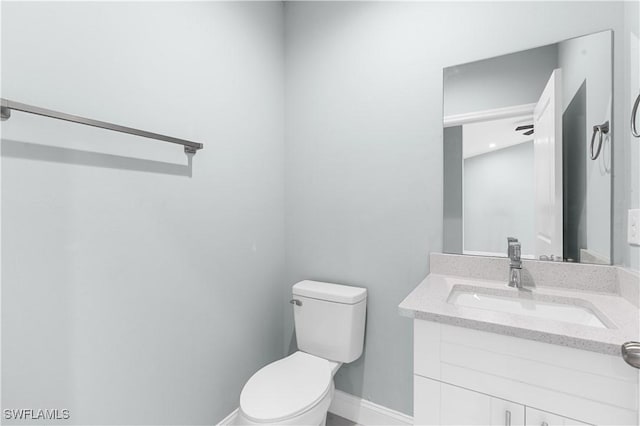 bathroom with baseboards, toilet, and vanity