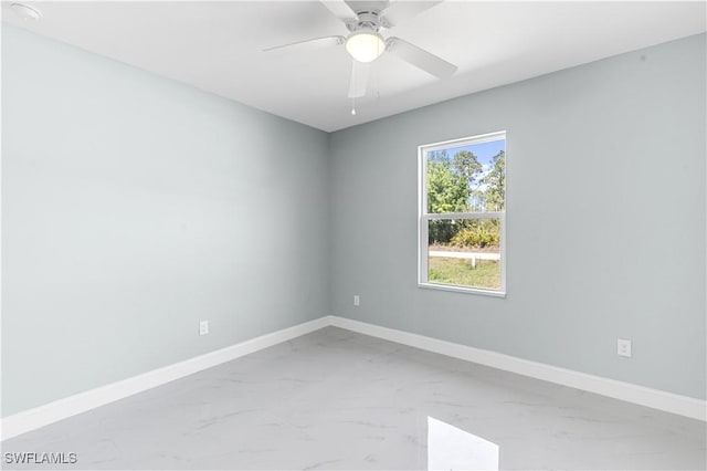 spare room featuring baseboards, marble finish floor, and a ceiling fan