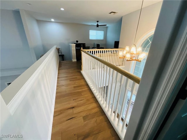 hall featuring recessed lighting, visible vents, an inviting chandelier, an upstairs landing, and wood finished floors