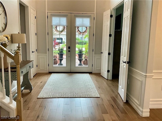 doorway featuring french doors, light wood-type flooring, and a decorative wall