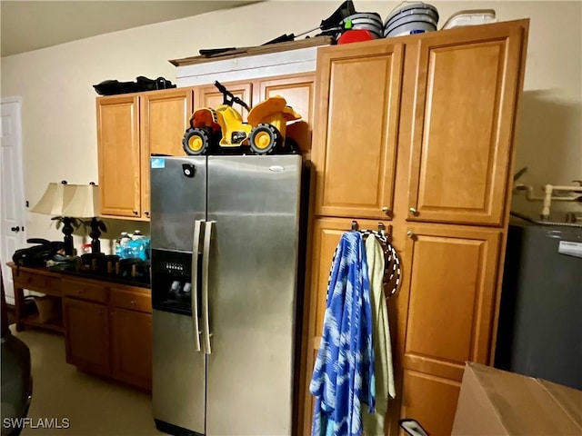 kitchen featuring dark countertops, water heater, brown cabinetry, and stainless steel refrigerator with ice dispenser