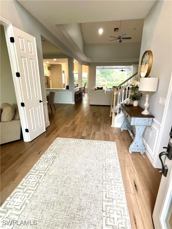 foyer featuring stairs, a wainscoted wall, light wood-style flooring, and a decorative wall