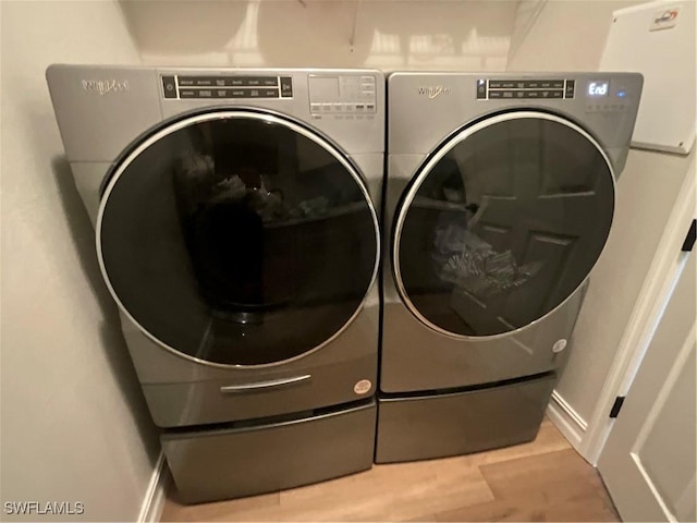 laundry room with laundry area, washing machine and dryer, baseboards, and light wood-style flooring