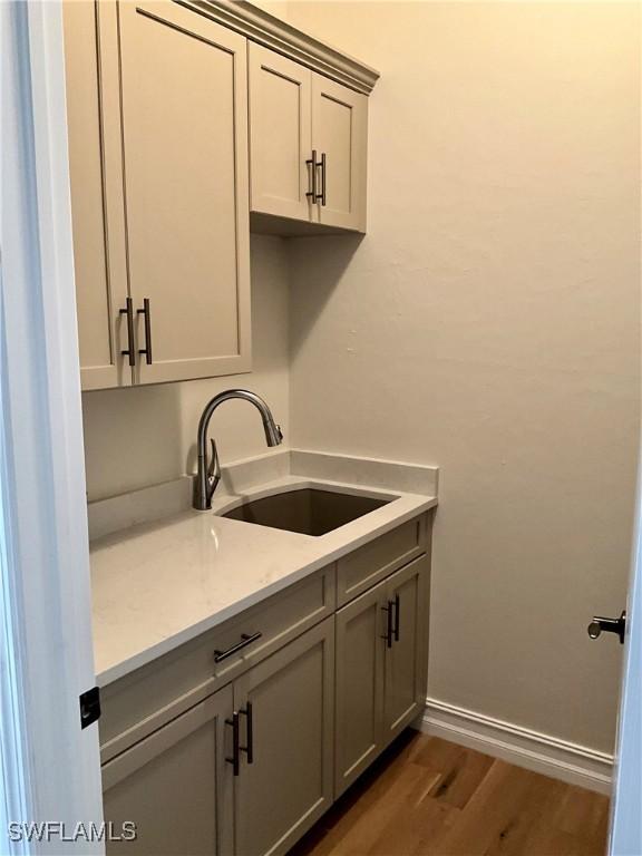 washroom featuring dark wood-style floors, baseboards, and a sink