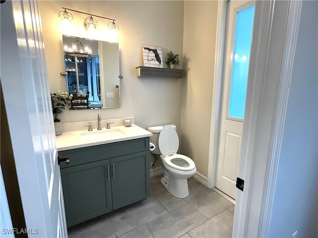 half bath featuring toilet, tile patterned flooring, vanity, and baseboards