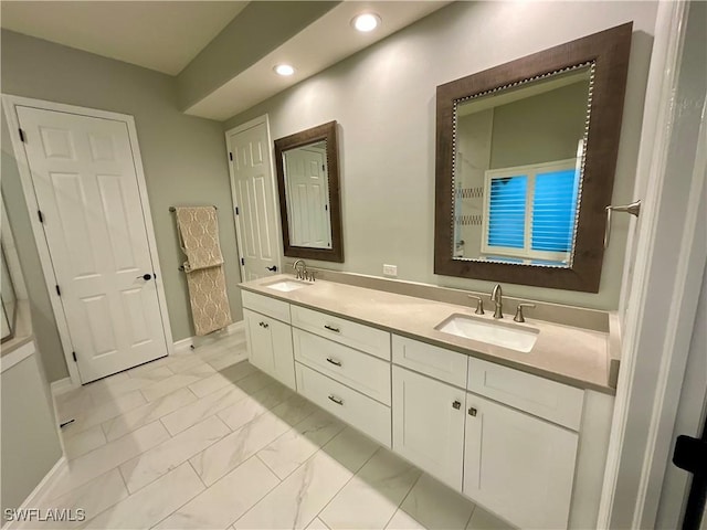 bathroom featuring marble finish floor, double vanity, a sink, and recessed lighting