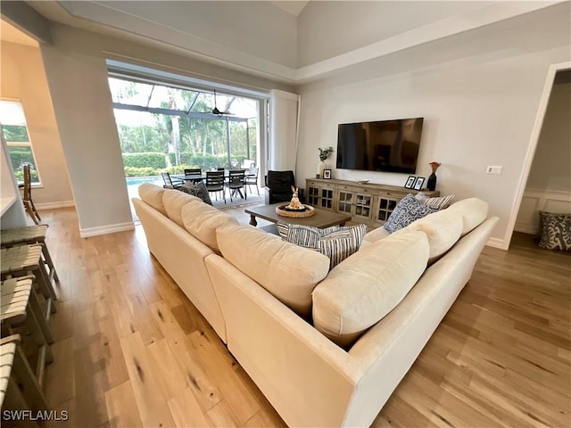 living area with light wood finished floors, plenty of natural light, baseboards, and a sunroom