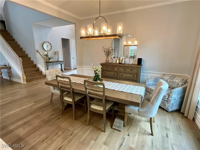 dining area featuring wainscoting, light wood-style flooring, and stairs