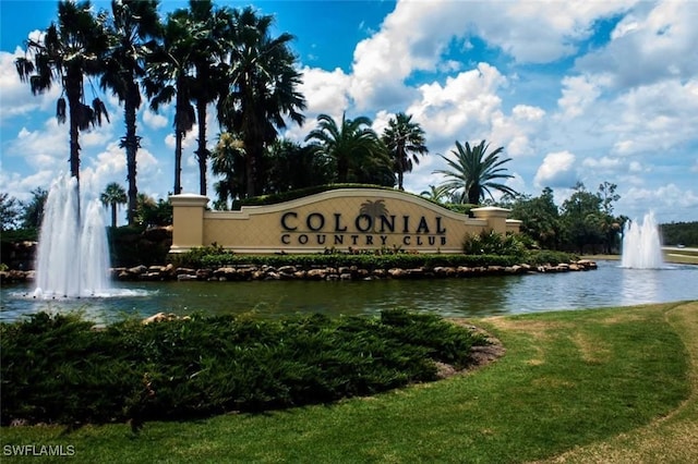 community sign featuring a water view and a lawn