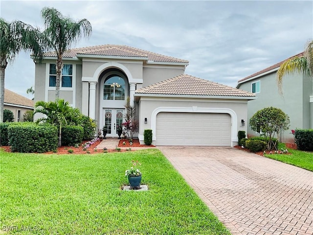 mediterranean / spanish home featuring decorative driveway, french doors, stucco siding, an attached garage, and a front yard