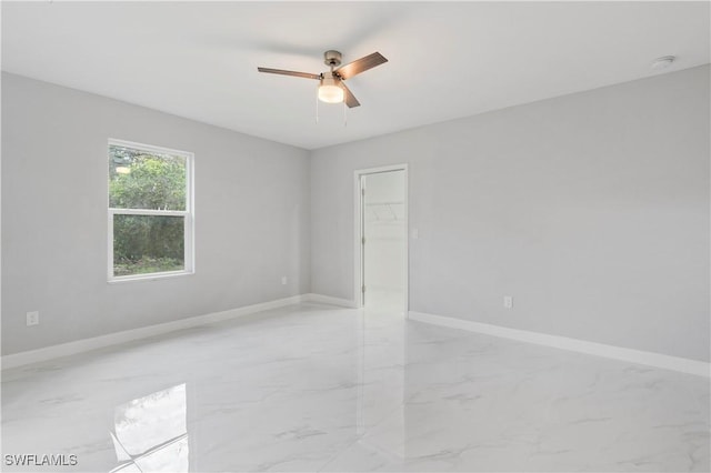 spare room featuring marble finish floor, ceiling fan, and baseboards