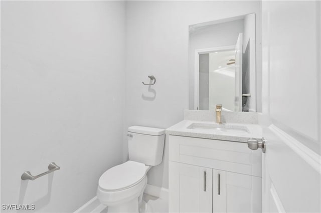 half bathroom with toilet, baseboards, and vanity