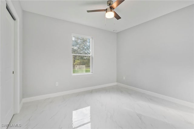 interior space featuring marble finish floor, a ceiling fan, and baseboards