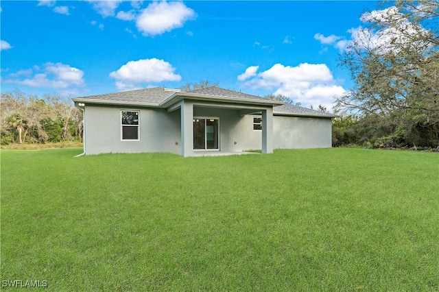 rear view of property with a lawn and stucco siding