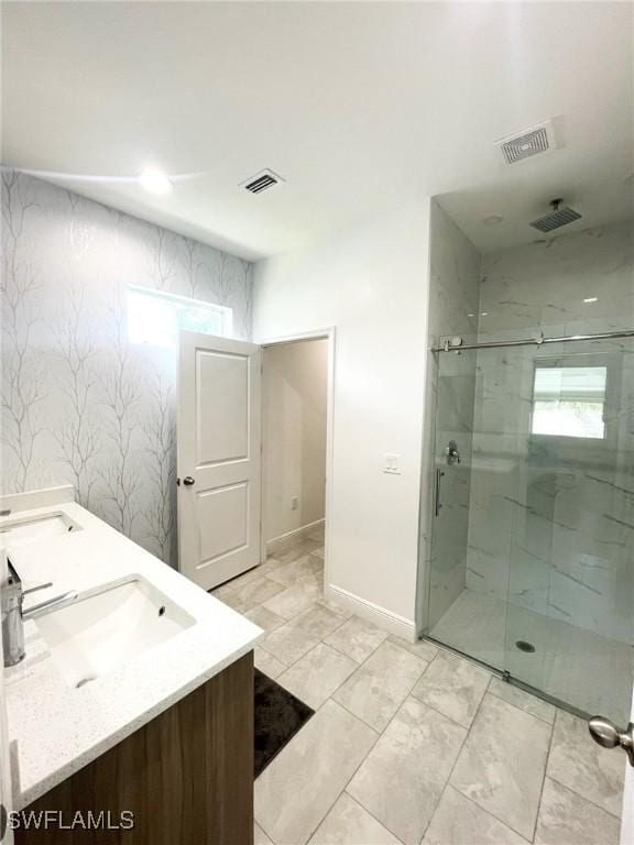 bathroom with double vanity, a marble finish shower, visible vents, and a sink