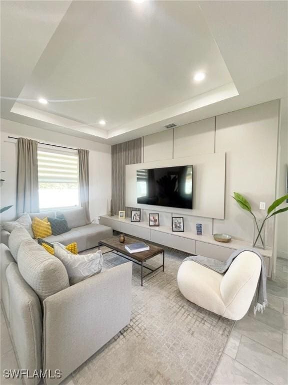 living area with visible vents, a raised ceiling, and recessed lighting