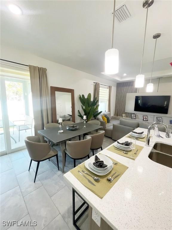 kitchen with light stone counters, a wealth of natural light, visible vents, and a sink