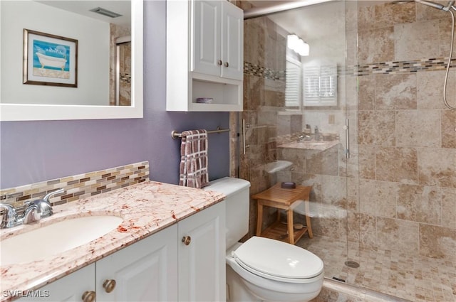 full bathroom featuring visible vents, toilet, decorative backsplash, a stall shower, and vanity