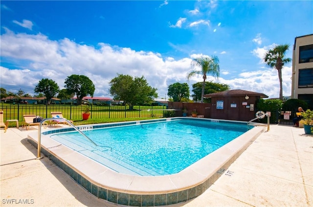 pool with a patio area, a yard, an outdoor structure, and fence