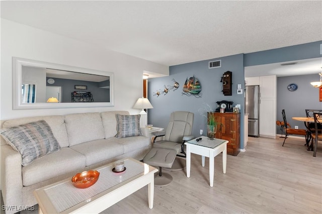 living area featuring light wood-style floors, visible vents, baseboards, and an inviting chandelier