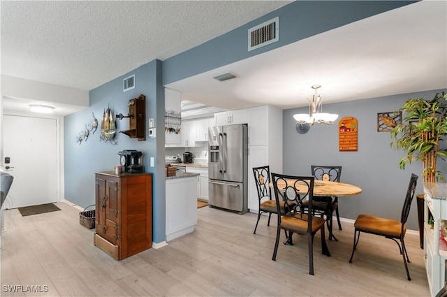 kitchen with white cabinets, light wood finished floors, visible vents, and stainless steel fridge with ice dispenser