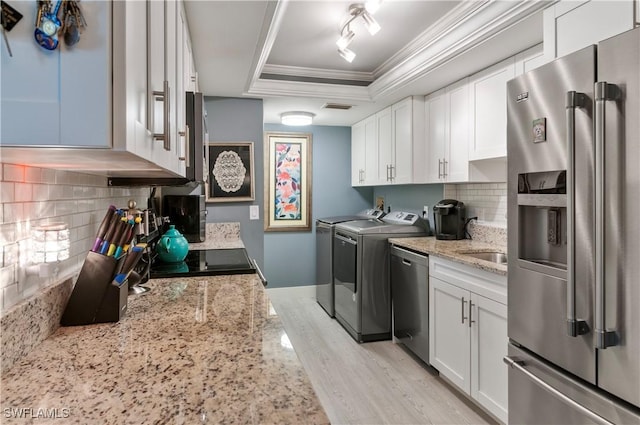 washroom with laundry area, baseboards, washer and clothes dryer, ornamental molding, and light wood-type flooring