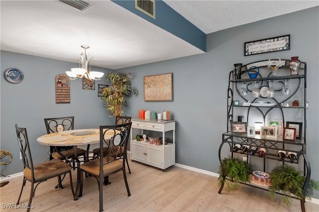 dining space featuring light wood-style floors, visible vents, and an inviting chandelier