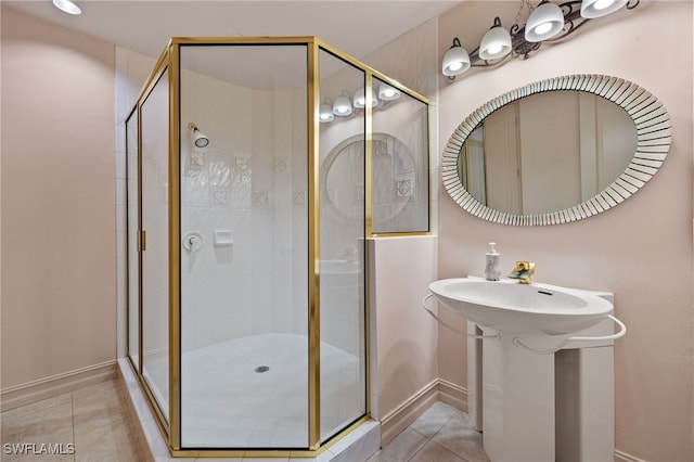 bathroom with a stall shower, baseboards, and tile patterned floors