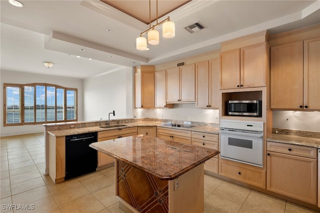 kitchen featuring visible vents, a raised ceiling, black appliances, light brown cabinets, and a sink