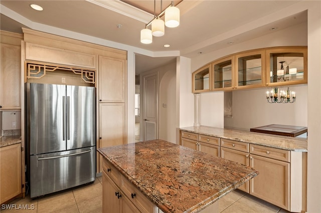 kitchen with glass insert cabinets, light brown cabinets, freestanding refrigerator, and light stone countertops