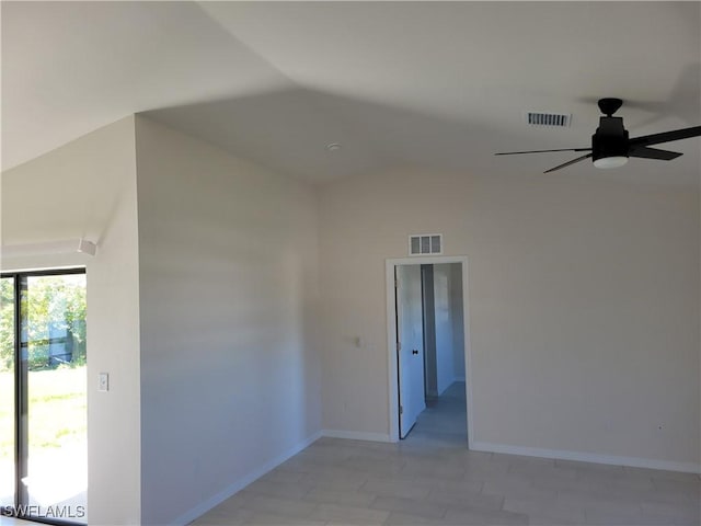 empty room featuring lofted ceiling, visible vents, ceiling fan, and baseboards