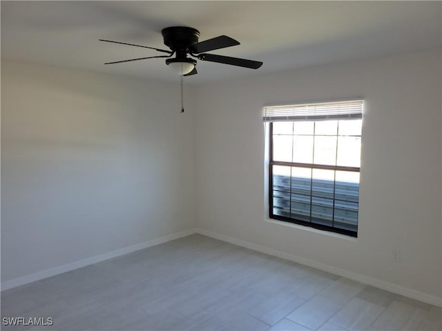 spare room with ceiling fan and baseboards