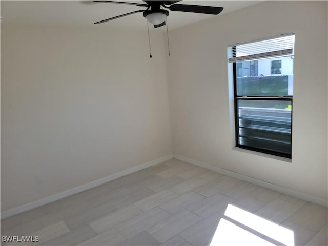 spare room with a ceiling fan and baseboards