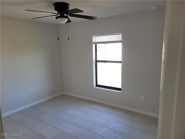 empty room with a ceiling fan and baseboards