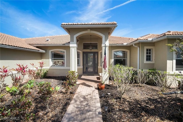 doorway to property featuring a tile roof and stucco siding