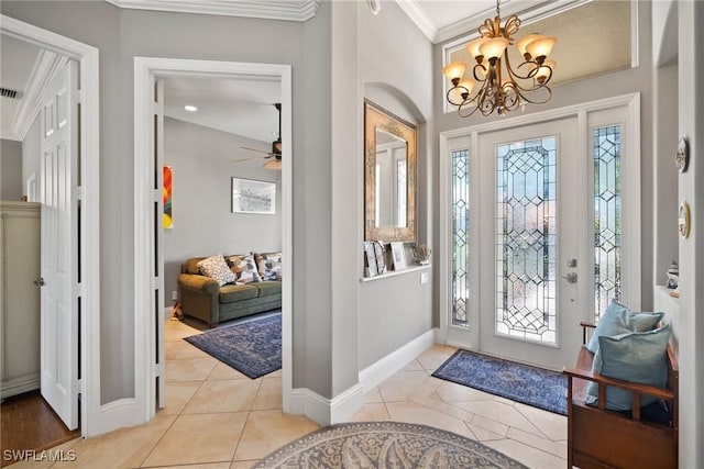 foyer with light tile patterned floors, ornamental molding, a chandelier, and baseboards