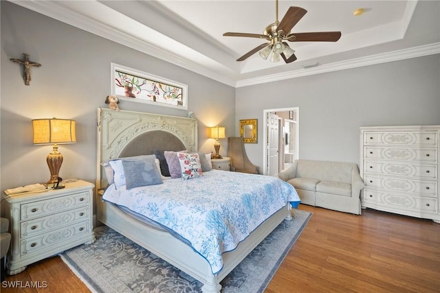 bedroom featuring ornamental molding, a raised ceiling, visible vents, and wood finished floors