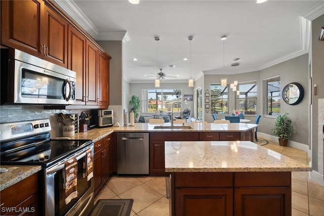 kitchen featuring light tile patterned floors, appliances with stainless steel finishes, a sink, and decorative light fixtures