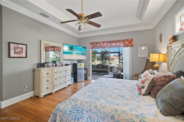 bedroom with access to exterior, a raised ceiling, visible vents, freestanding refrigerator, and light wood-type flooring