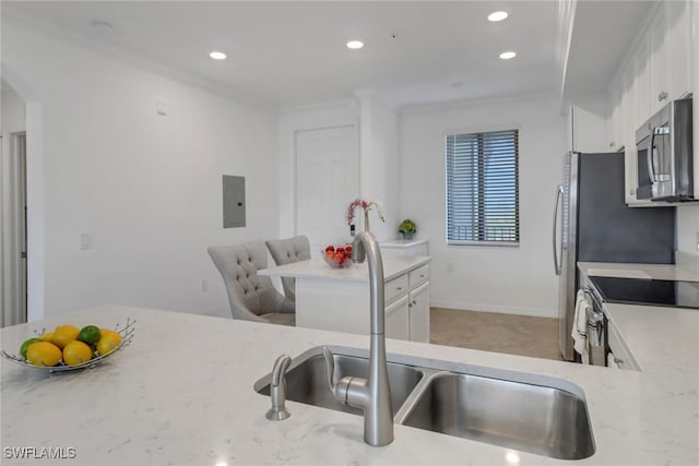 kitchen featuring stainless steel appliances, a sink, white cabinetry, ornamental molding, and light stone countertops