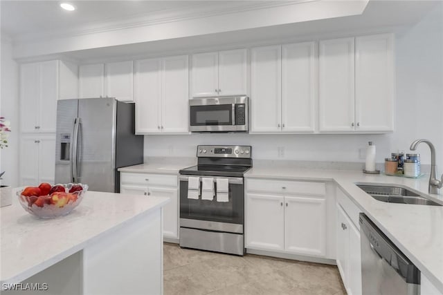 kitchen with light stone counters, stainless steel appliances, ornamental molding, white cabinets, and a sink