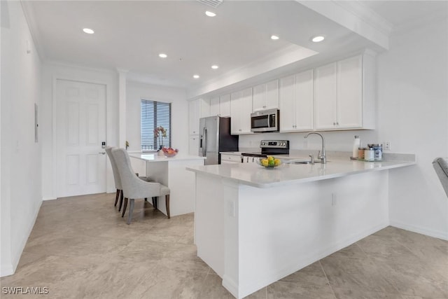 kitchen featuring a peninsula, a sink, light countertops, ornamental molding, and appliances with stainless steel finishes