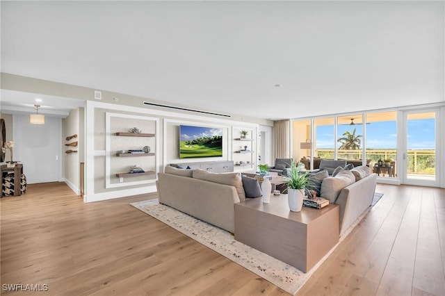 living area with built in shelves, floor to ceiling windows, and light wood finished floors