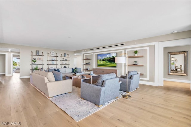 living area featuring built in features, baseboards, and light wood-style floors