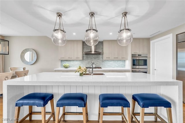 kitchen with backsplash, light countertops, wall chimney exhaust hood, and a sink